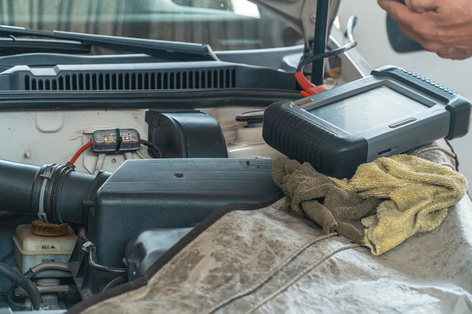 Diagnostic scan tool connected to a vehicle engine bay