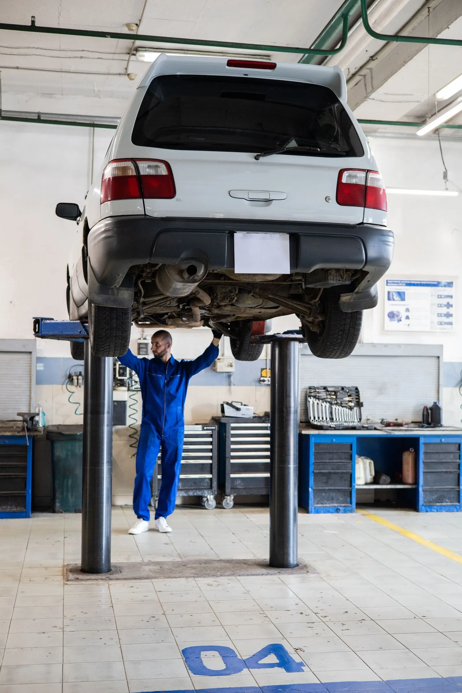 Technician working under a vehicle raised on a lift