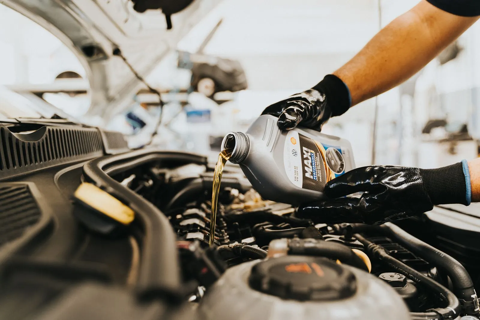 Technician pouring fresh engine oil into a car engine