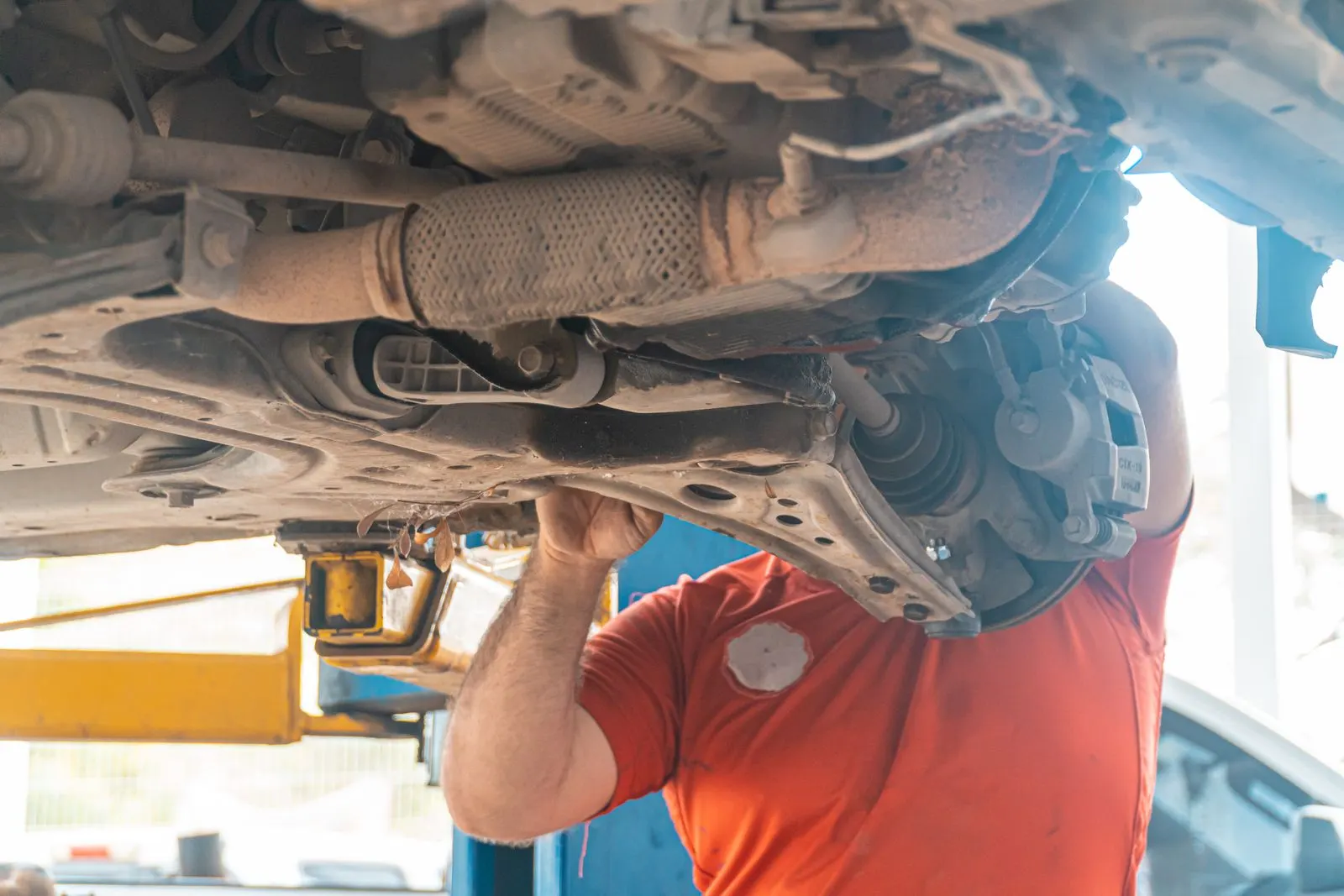 Technician inspecting a vehicle's undercarriage and suspension