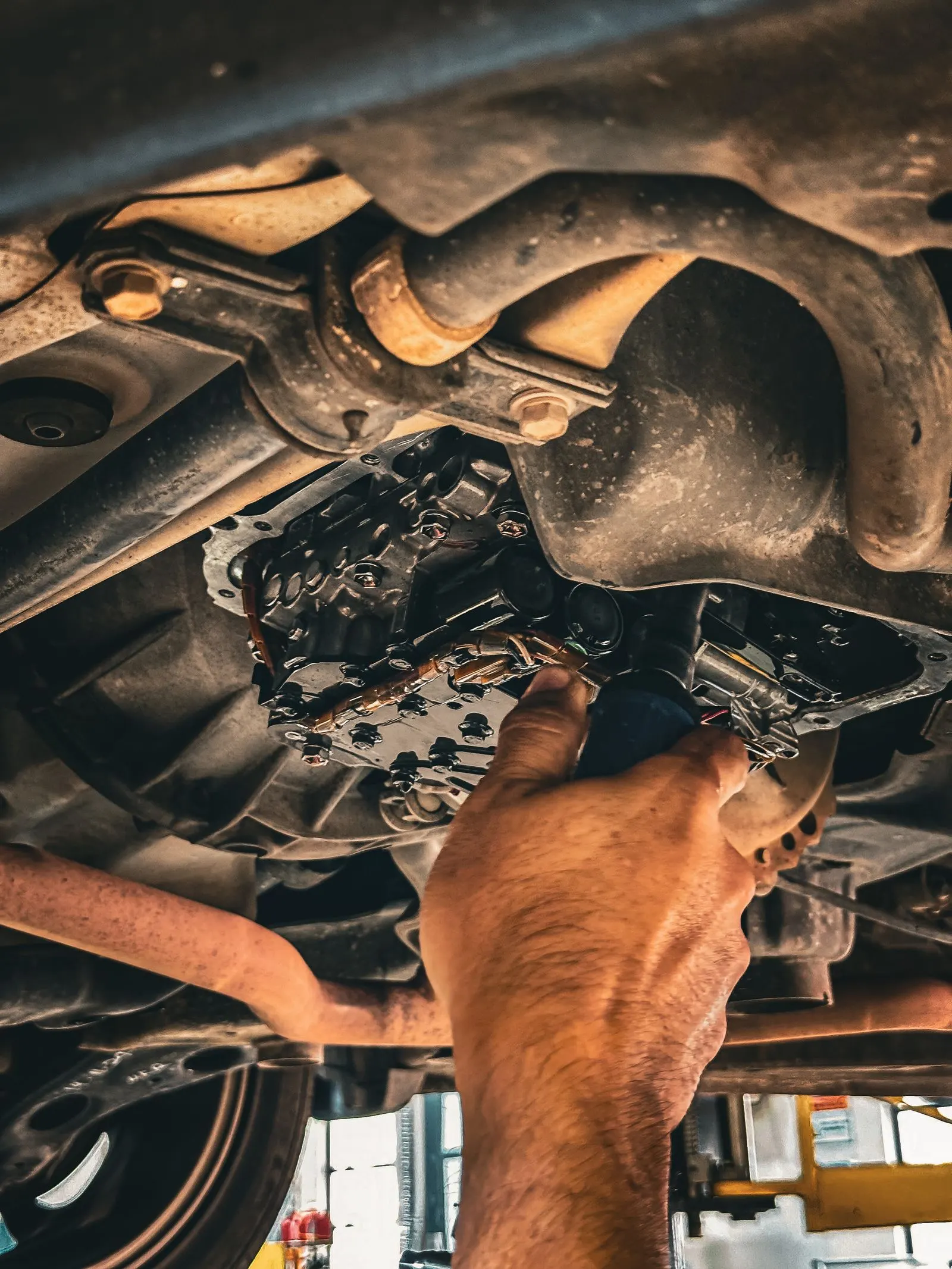 Technician working on a vehicle transmission from underneath