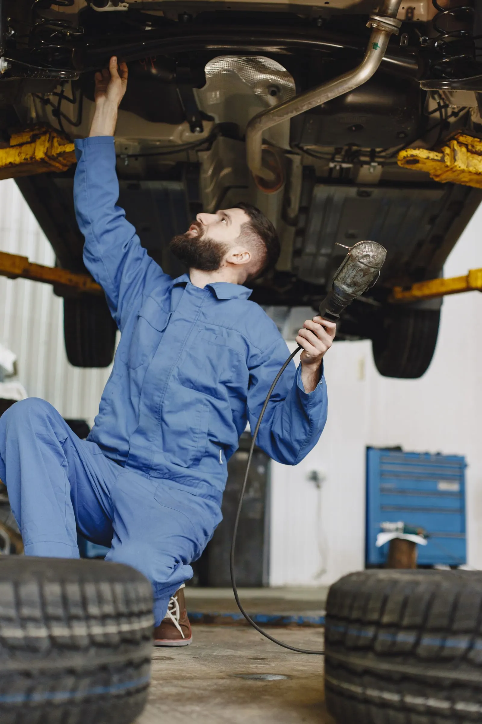 Technician inspecting the underside of a vehicle